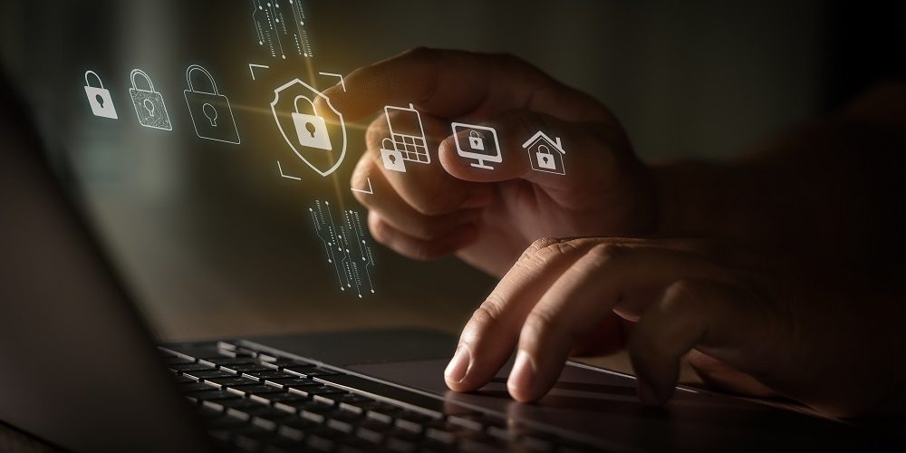 Imagem das Mãos de um homem digitando em seu notebook e trabalhando para melhorar a cibersegurança do seu provedor