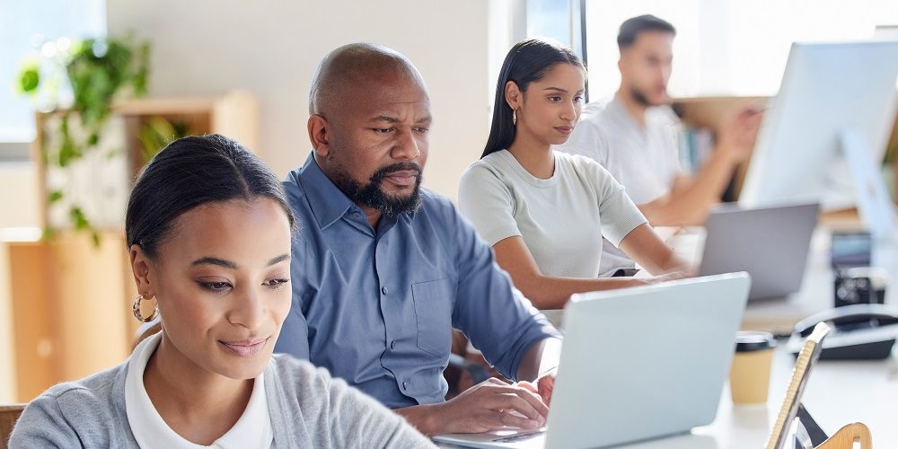 Grupo de colaboradores trabalhando em laptops com acesso a um plano de internet para empresas.