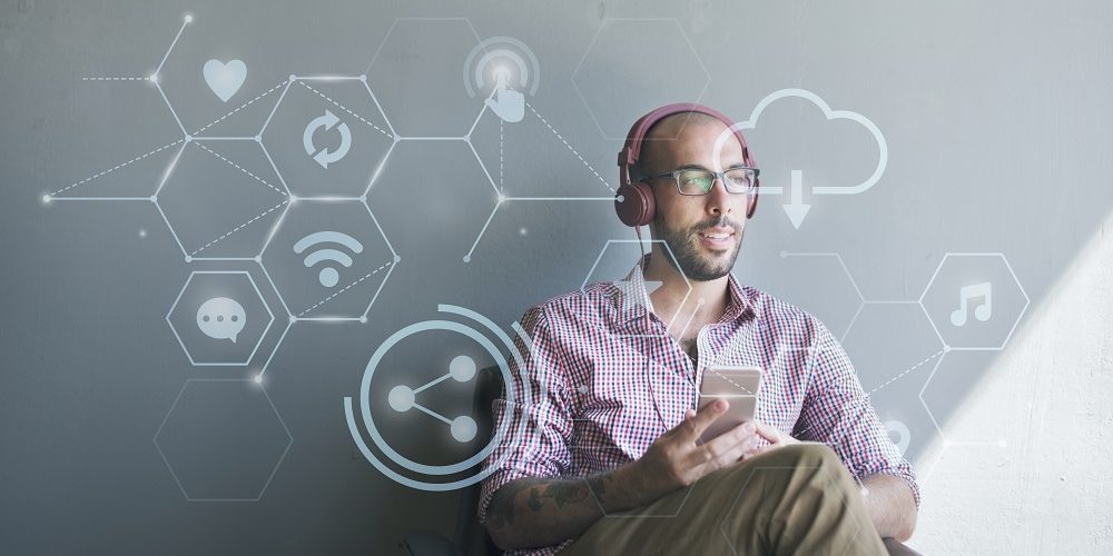 Imagem de um homem sentado com o celular na mão, pensando em vários assuntos de tecnologia.